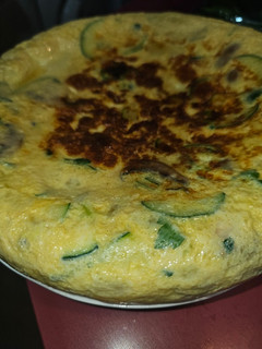 Una foto de Tortilla de patata, calabacín, champis y cebolla de ensalada con ajo y perejil