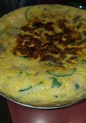 Una foto de Tortilla de patata, calabacín, champis y cebolla de ensalada con ajo y perejil