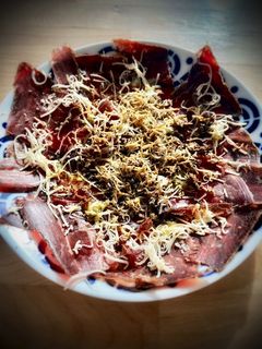 Una foto de Cecina de León con queso curado y trufa negra
