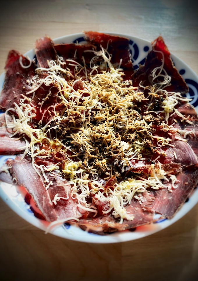 Una foto de Cecina de León con queso curado y trufa negra