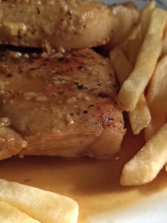 Una foto de Costeleta de Cerdo con Papas Fritas rebozadas en un jarabe de Mostaza a la miel con vino