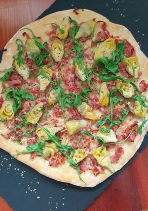 Una foto de Pizza de alcachofas, jamón y rúcula