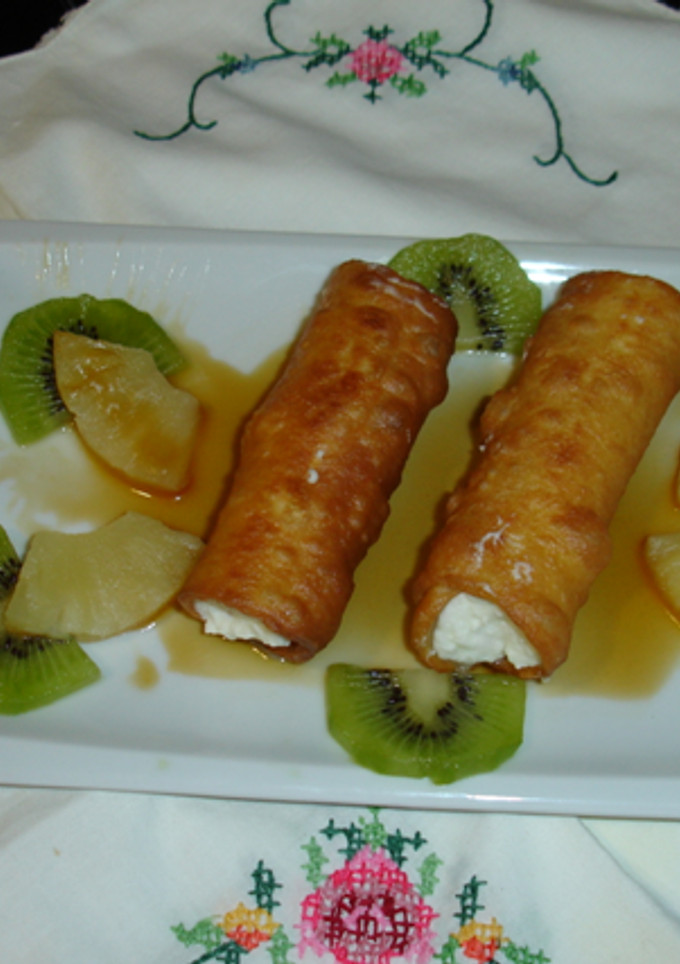 Una foto de Canutillos fritos rellenos de nata con fruta de la pasión, piña y salsa de naranja 