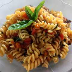 A picture of Fideos espirales con tomate, albahaca y aceitunas.