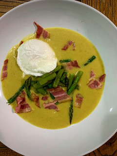 Una foto de Sopa de curry y manzana, espárragos, huevo poché y bacon