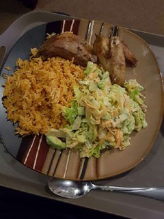 A picture of Jollof rice with salad and chicken wings.