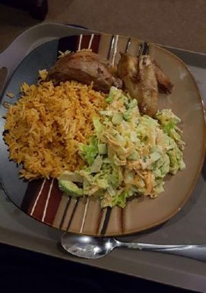A picture of Jollof rice with salad and chicken wings.