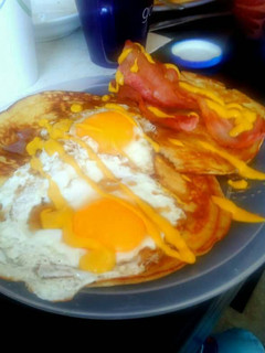 Una foto de Huevos fritos con tocino y hotcakes