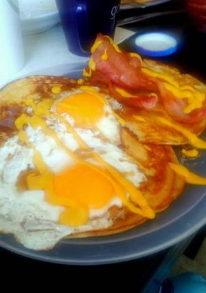 Una foto de Huevos fritos con tocino y hotcakes