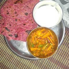 A picture of Beetroot paratha with curd and sabji.