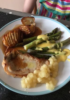 A picture of Brined Pork Chops with Hasselback Potatoes, tender, buttery Asparagus and sharp Hollandaise Sauce.