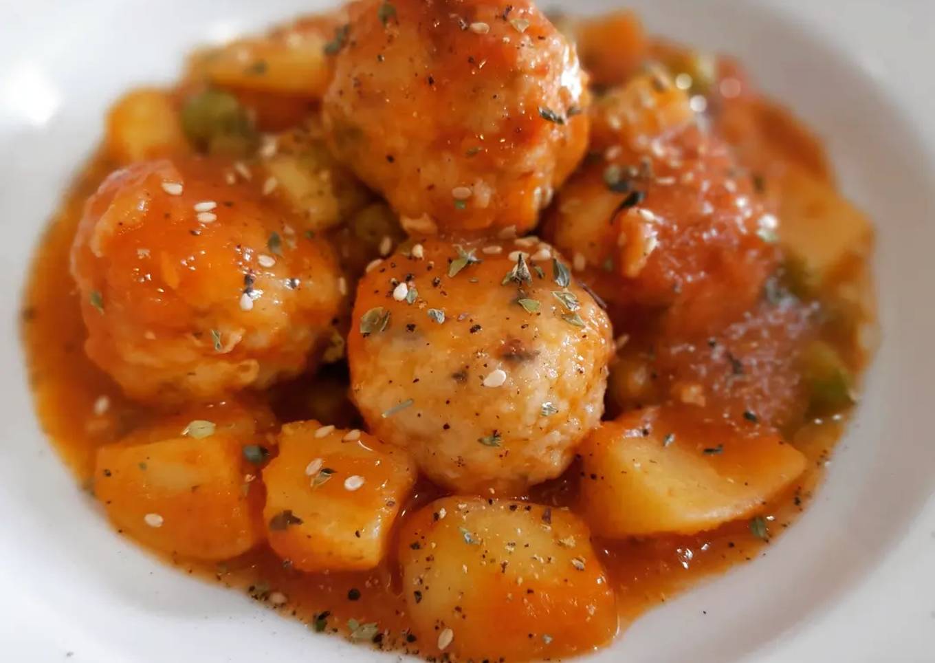 Albóndigas de merluza en salsa con patatas y guisantes