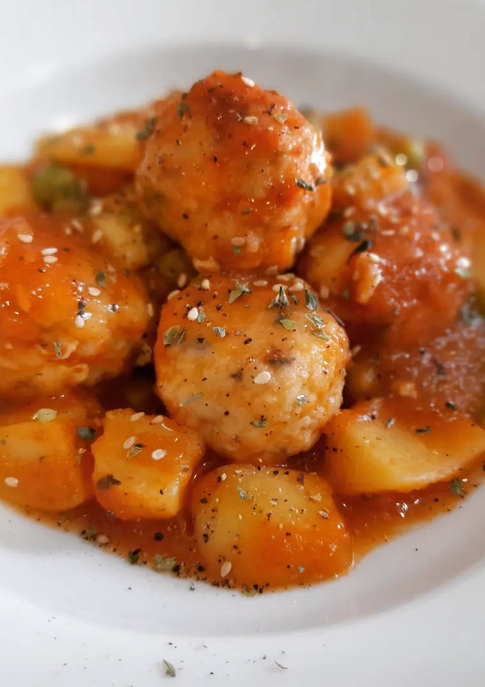Una foto de Albóndigas de merluza en salsa con patatas y guisantes