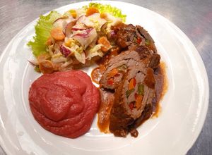 Una foto de Rollo de carne, ensalada de frutas y puré de papas con remolacha