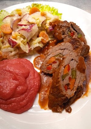 Una foto de Rollo de carne, ensalada de frutas y puré de papas con remolacha