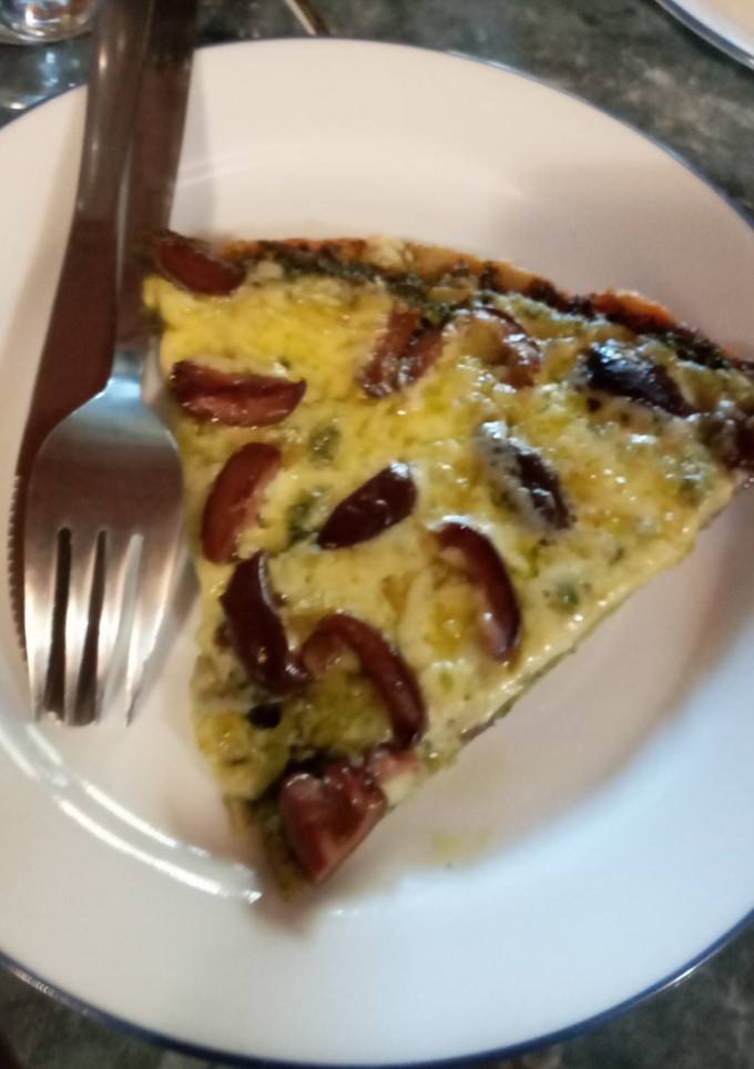 Una foto de Pizza con pesto, queso mantecoso y aceitunas negras