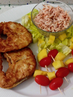 Una foto de Merluza frita con camarones cocidos y ensalada de pinchos de tomatitos con mango