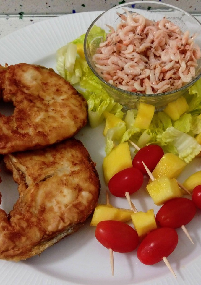 Una foto de Merluza frita con camarones cocidos y ensalada de pinchos de tomatitos con mango