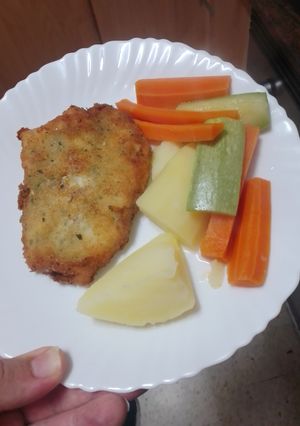 Una foto de Merluza empanada con papas y verduras cocidas