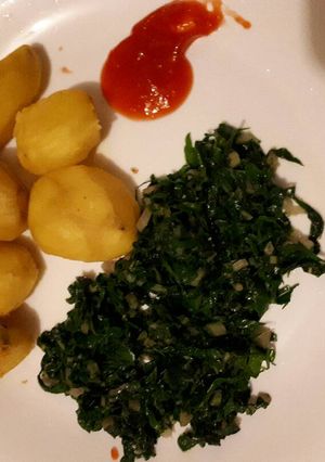 A picture of Tumeric roast potatoes served with spinach.