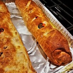 A picture of Sausage Pepper & Broccoli Rabe Calzone with Roasted Peppers & Mozzarella.
