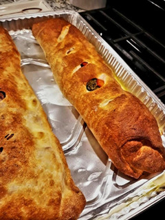 A picture of Sausage Pepper & Broccoli Rabe Calzone with Roasted Peppers & Mozzarella.