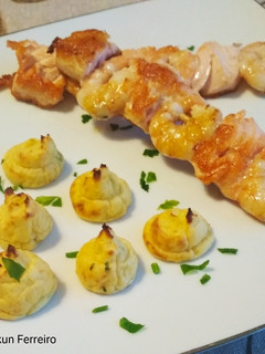 Una foto de Patatas duquesa con brochetas de salmón y langostinos