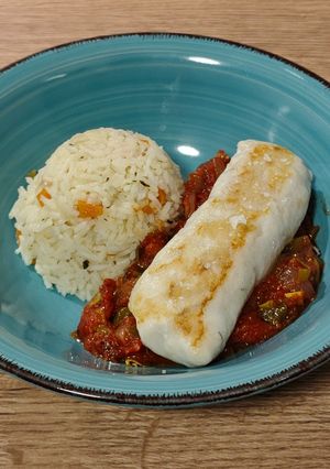 Una foto de Merluza a la plancha con salsa de tomate y guarnición de arroz pilaf con zanahoria