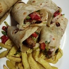 A picture of Chicken wrap sandwich with potato wedges.