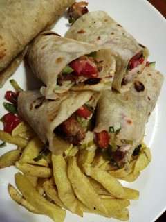A picture of Chicken wrap sandwich with potato wedges.