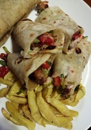 A picture of Chicken wrap sandwich with potato wedges.
