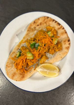 A picture of Chicken tikka on naan with fragrant salad.