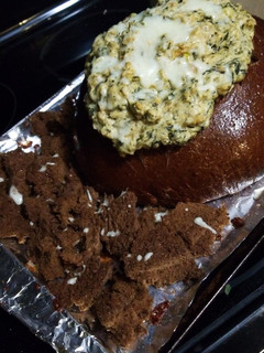 A picture of Cheesy Spinach Dip in a Pumpernickel Bread Bowl.