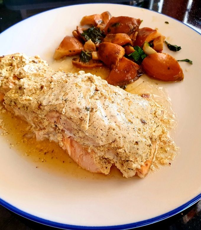 Foto principal de Salmón al papillote con costra de queso ricotta y salsa harissa acompañado por rovellons salteados