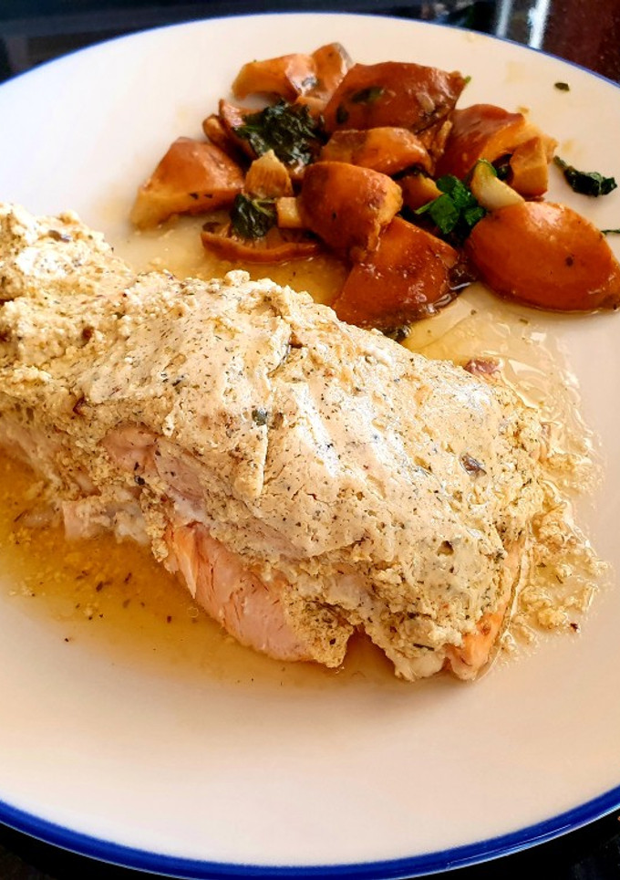 Una foto de Salmón al papillote con costra de queso ricotta y salsa harissa acompañado por rovellons salteados