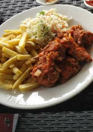 A picture of Chips,coleslaw and sauced meat.