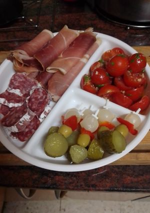 Una foto de Tomates cherry al ajillo con fuet, jamón serrano y encurtidos