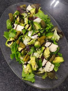 Una foto de Ensalada de brotes tiernos, aguacate y rulo de cabra