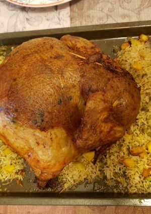 A picture of Chicken stuffed with rice, potatoes and green peas.