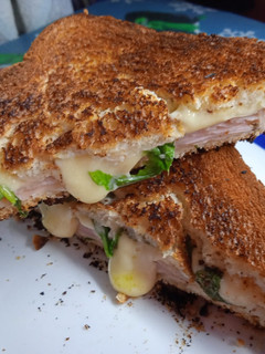 Una foto de Sándwich tostado de jamón, queso y rúcula en sartén