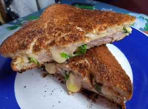 Una foto de Sándwich tostado de jamón, queso y rúcula en sartén