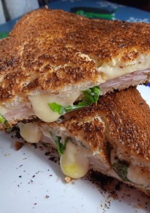 Una foto de Sándwich tostado de jamón, queso y rúcula en sartén