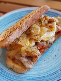 Una foto de Bocata de secreto ibérico gratinado, pimiento asado y huevo frito con cebolla caramelizada