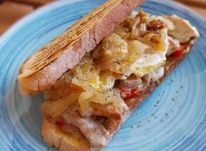 Foto principal de Bocata de secreto ibérico gratinado, pimiento asado y huevo frito con cebolla caramelizada