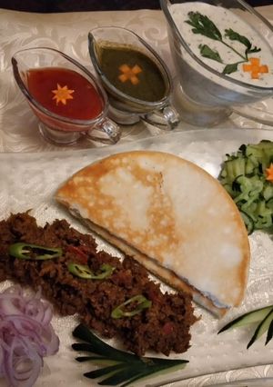 A picture of Beef shawarma With pita bread and sauces.