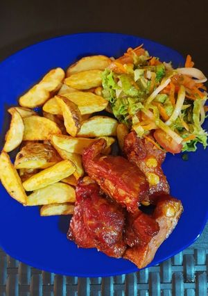 Una foto de Costillas bbq acompañadas de papas en cascos especiadas y ensalada de lechuga