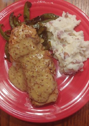 A picture of Pan seared pork chop with mustard sauce and green peppers.