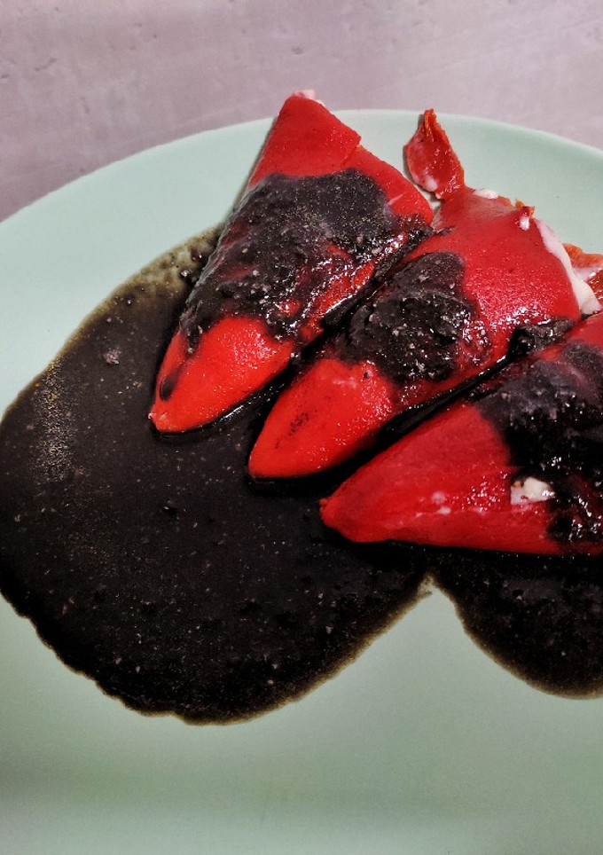 Una foto de Pimientos de piquillo rellenos de chipirón y salsa negra