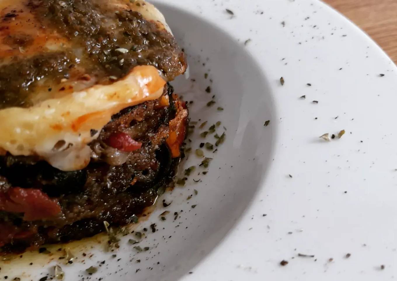 Milhojas de berenjena empanada, puttanesca gratinada con pesto
