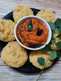 A picture of Moong Dal Idli with red chutney.